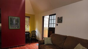 Un salon avec un canapé marron, deux coussins, un tableau encadré accroché au mur et un mur rouge.