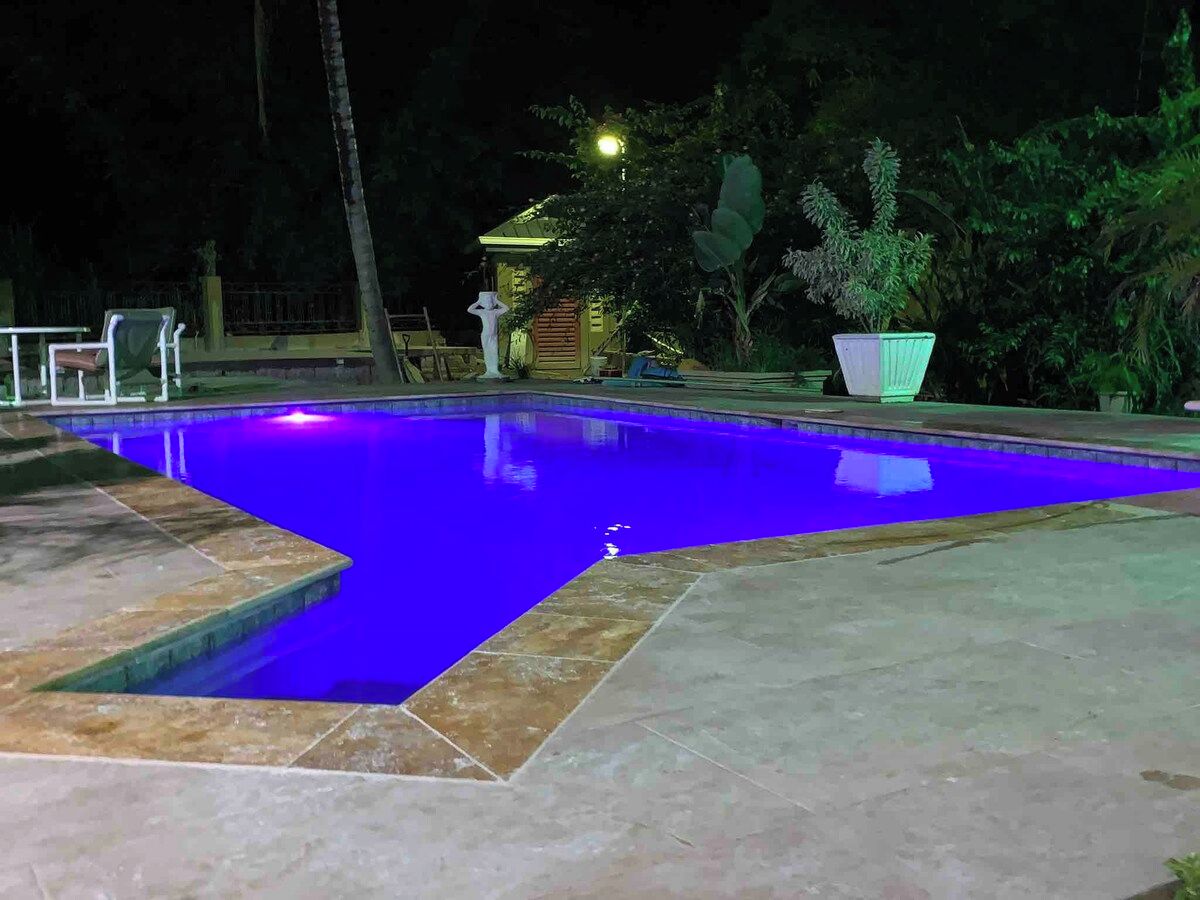 Une piscine à l’eau bleutée, entourée d’une terrasse en pierre et agrémentée de plantes en pot.