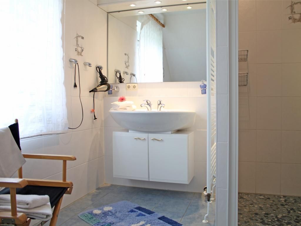 A bathroom with a white sink, a mirror, and a shower area.