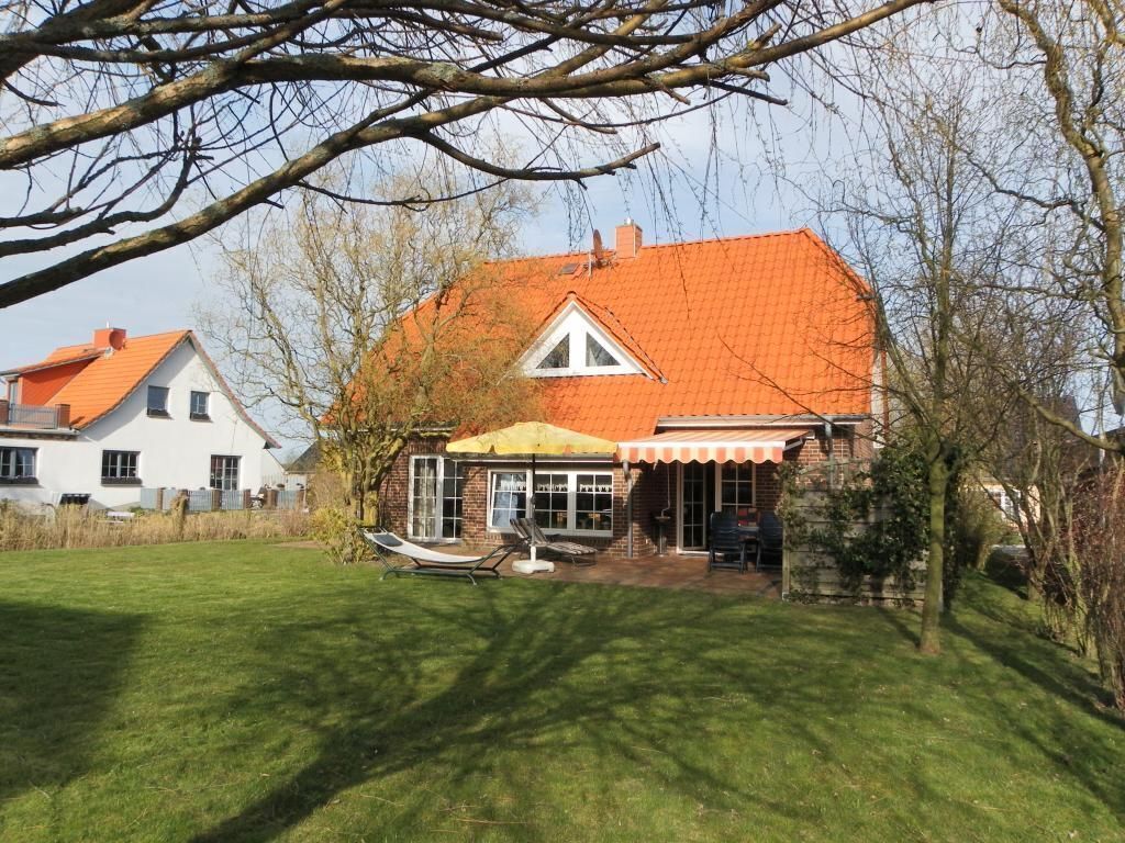 Ein Haus mit rotem Dach, überdachter Terrasse und Rasen.