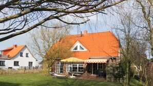A house with a red roof, a covered patio, and a lawn. - Sonnenblick holiday house (Kalkhorst)