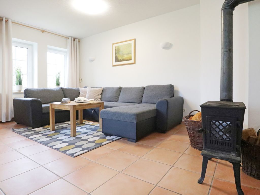 Een gezellige woonkamer met een bank, een tafel en een houtkachel.