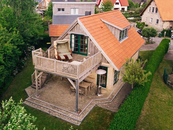 A two-story house with a balcony, a wooden deck, and a small patio area.