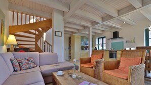 Ein geräumiges Wohnzimmer mit einer Couch, Korbsesseln, einem Couchtisch und einer Treppe.
