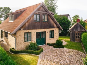 A traditional wooden house with a stone pathway leading to the entrance.