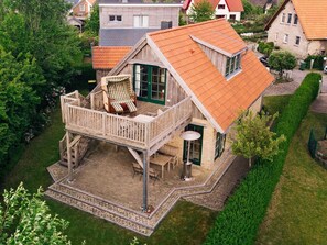 A two-story house with a balcony, a wooden deck, and a small patio area.