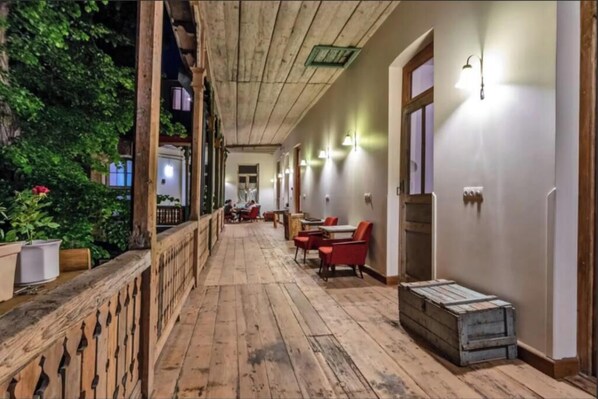 Stroll through this inviting corridor lined with potted plants and natural light fixtures, leading to a cozy seating area with comfortable chairs and tables.