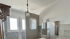 Een moderne badkamer met douche, wastafel en wasmachine.