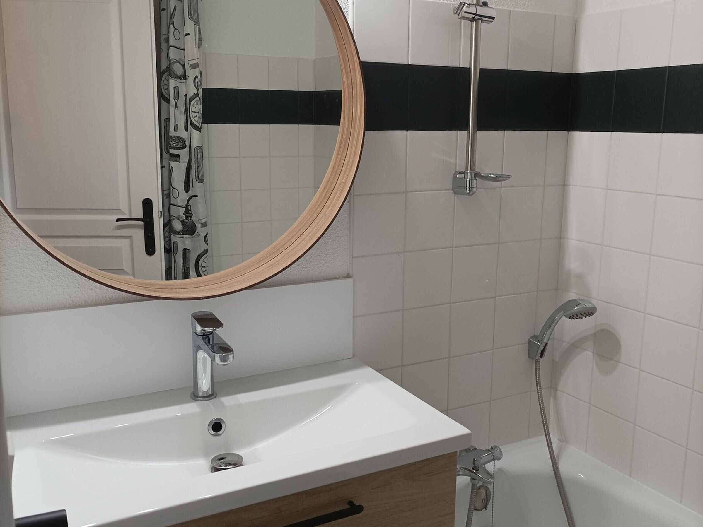 A bathroom with a white sink, a mirror, a shower, and a towel rack.