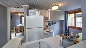 Una cocina compacta equipada con refrigerador, estufa, microondas y utensilios colgantes.