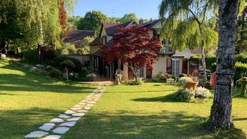 A house with a stone pathway leading to the entrance, surrounded by well-maintained lawns and trees.