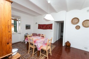 A dining area with a table set for four, a hanging light fixture, and a patterned floor. - S190 - Sirolo, three-room apartment in the square (Sirolo)
