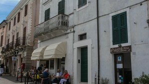 Una strada con posti a sedere all'aperto, un caffè chiamato 'Osteria Zara' e un edificio con un balcone.