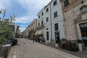A cobblestone street with buildings, outdoor seating, and potted plants. - S190 - Sirolo, three-room apartment in the square (Sirolo)