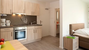 A modern kitchen with wooden cabinets, a built-in oven, and a sink. - Apartment Alma - Apartment Lühe (Jork)