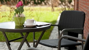 A patio with a table and chairs, a potted plant, and a cup. - Apartment Alma - Apartment Lühe (Jork)