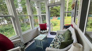 Eine überdachte Veranda mit Korbmöbeln, einem Tisch und einem Deckenventilator.