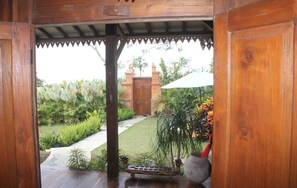 A wooden structure with a view of a garden and a brick building in the background.