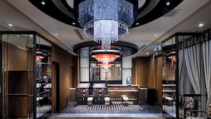 Een hotellobby met een weelderige kroonluchter, een receptiebalie en een zithoek.