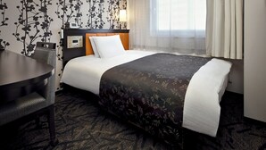 Een hotelkamer met een bed, een bureau en een stoel.