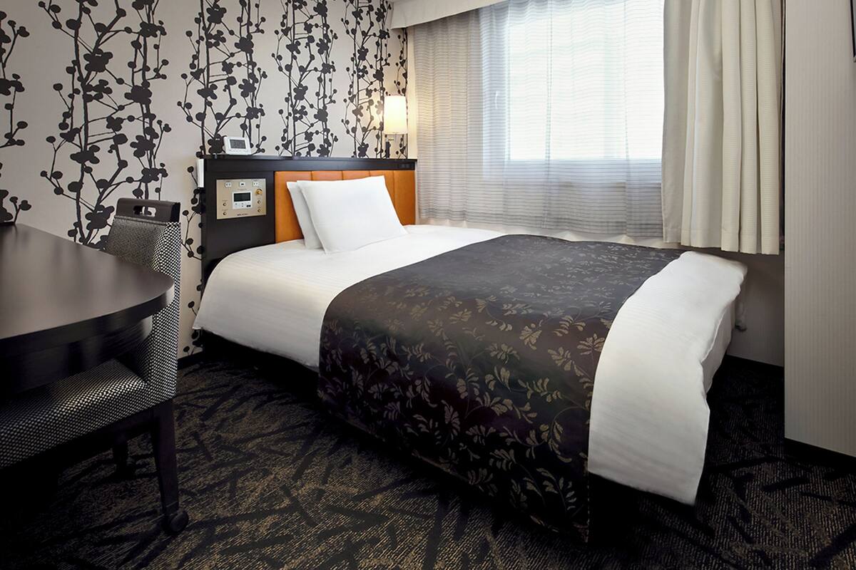 Une chambre d’hôtel avec un lit, un bureau et une chaise.