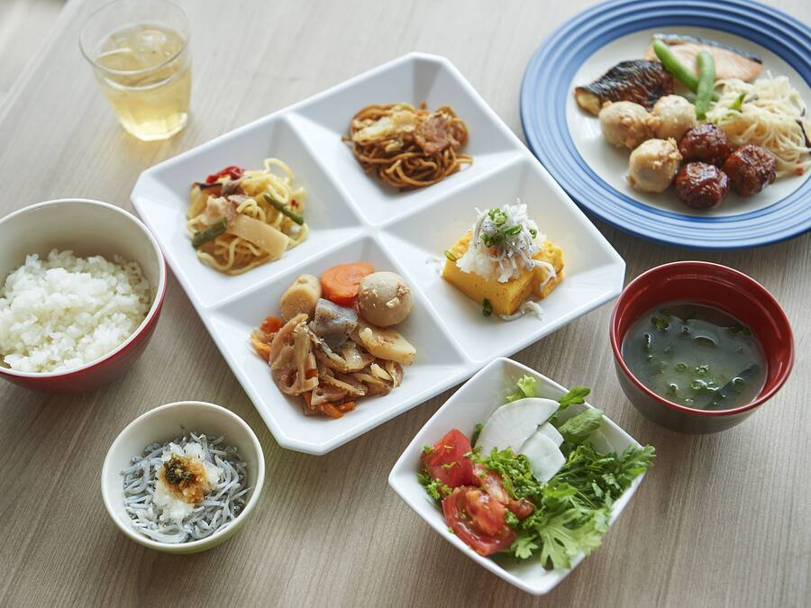 A variety of dishes including rice, noodles, and soup, arranged on a wooden table.
