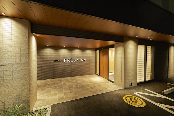 Ingresso moderno di un hotel con soffitto in legno, pavimento piastrellato e cartello con la scritta 'SOTSU FRESAINN'.
