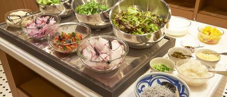 Una mesa de buffet con diferentes opciones de comida, incluyendo ensaladas, arroz y otros platos.