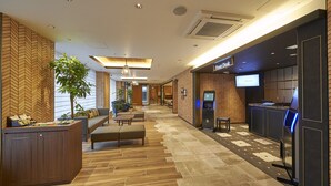 Un vestíbulo de hotel con una recepción, zona de estar y un bar.