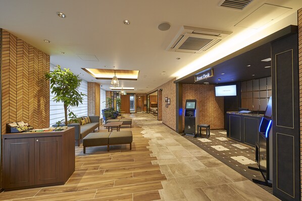 Una hall d'albergo con reception, area salotto e un bar.