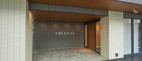 The entrance of the FréSa Inn with a tiled facade and a wooden ceiling.