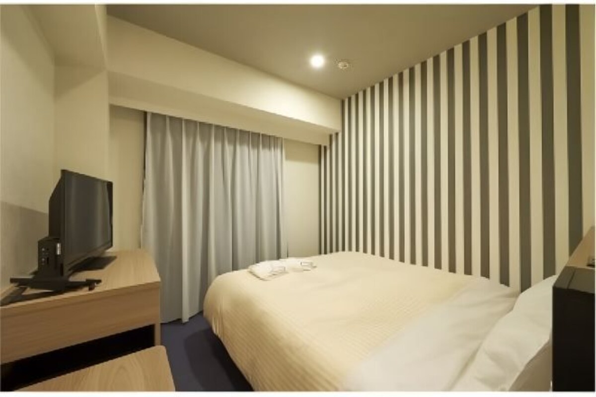 Una camera d'albergo con un letto, una scrivania con un computer e una televisione.