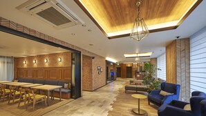 Un moderno vestíbulo de hotel con techo de madera, zonas de estar y una pared con patrón de espiga.