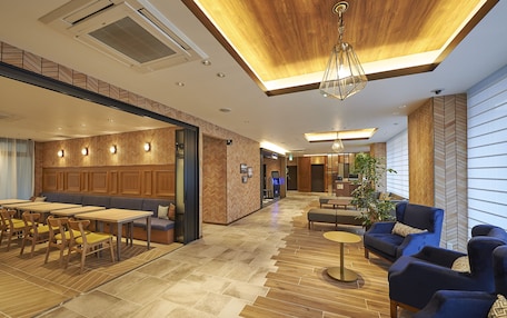A modern hotel lobby with a wooden ceiling, seating areas, and a herringbone-patterned wall.