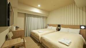 Habitación de hotel con dos camas, un escritorio, una silla, un televisor de pantalla plana y un ventanal con cortinas.