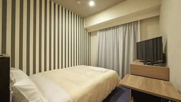 A hotel room with a bed, a TV on a wooden stand, a desk, and a striped wall.
