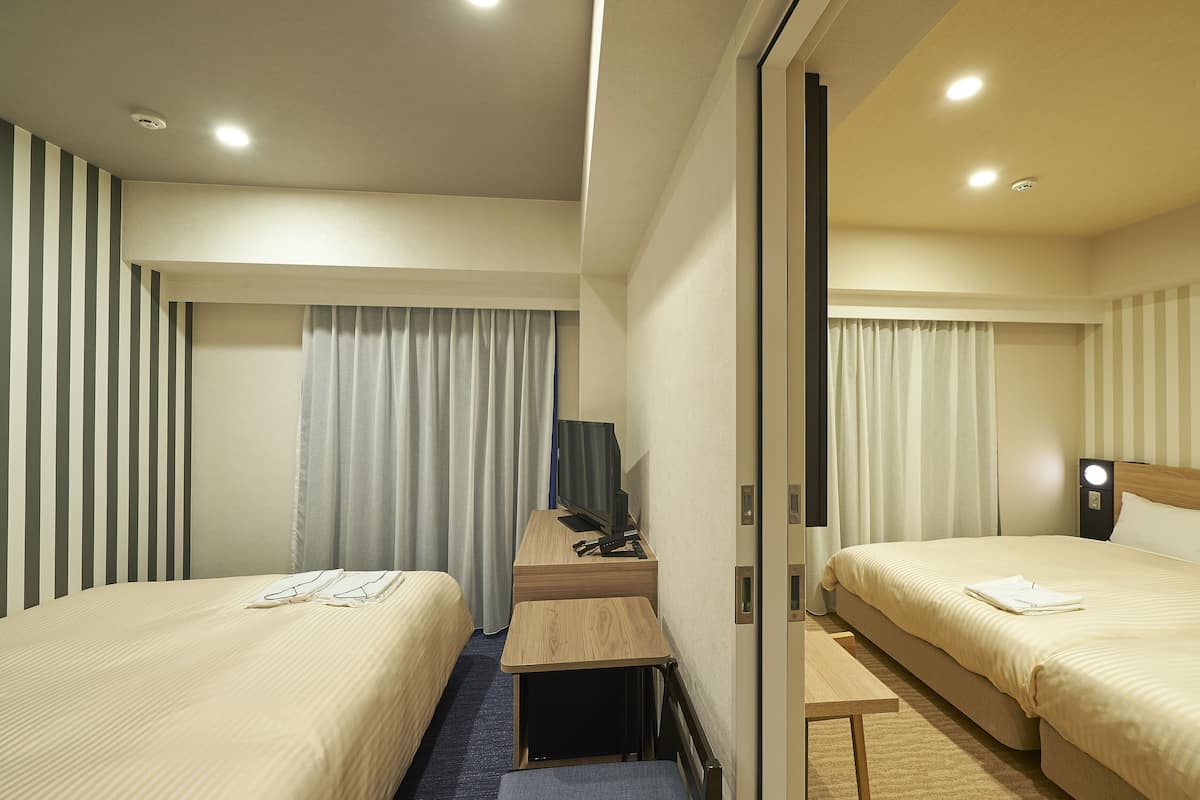 Een hotelkamer met twee bedden, een bureau en een televisie.