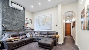 Una sala de estar con un sofá modular, un gran mapa mundial en la pared y un pasillo que conduce a una puerta de madera.