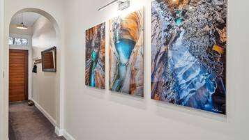A hallway with three large abstract paintings on the wall, a wooden door, and a carpeted floor.