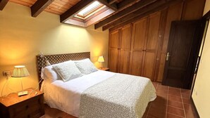 Une chambre à coucher avec un lit, deux lampes de chevet, une armoire en bois et un puits de lumière.