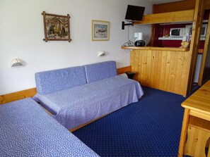 Two single beds with blue bedding, a wooden bench, and a small table make this room a comfortable retreat.