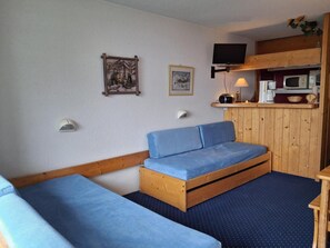 A room with a bed, a small table, a shelf with a TV, and wall-mounted lamps. - 100m from ski slopes, 1st floor, view valley, balcony, tv, 22m², Les Arcs (Les Arcs)