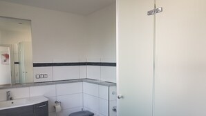 Een badkamer met toilet, wastafel en spiegel. Er zitten drie stopcontacten in de muur.