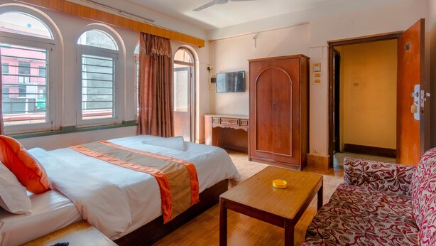 A hotel room with two beds, a desk, a wardrobe, a TV, and a ceiling fan. - Hotel River Holiday Inn (Kathmandu)