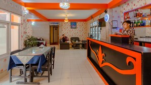 A restaurant with a bar area, a dining table with chairs, and a person standing at the bar. - Hotel River Holiday Inn (Kathmandu)
