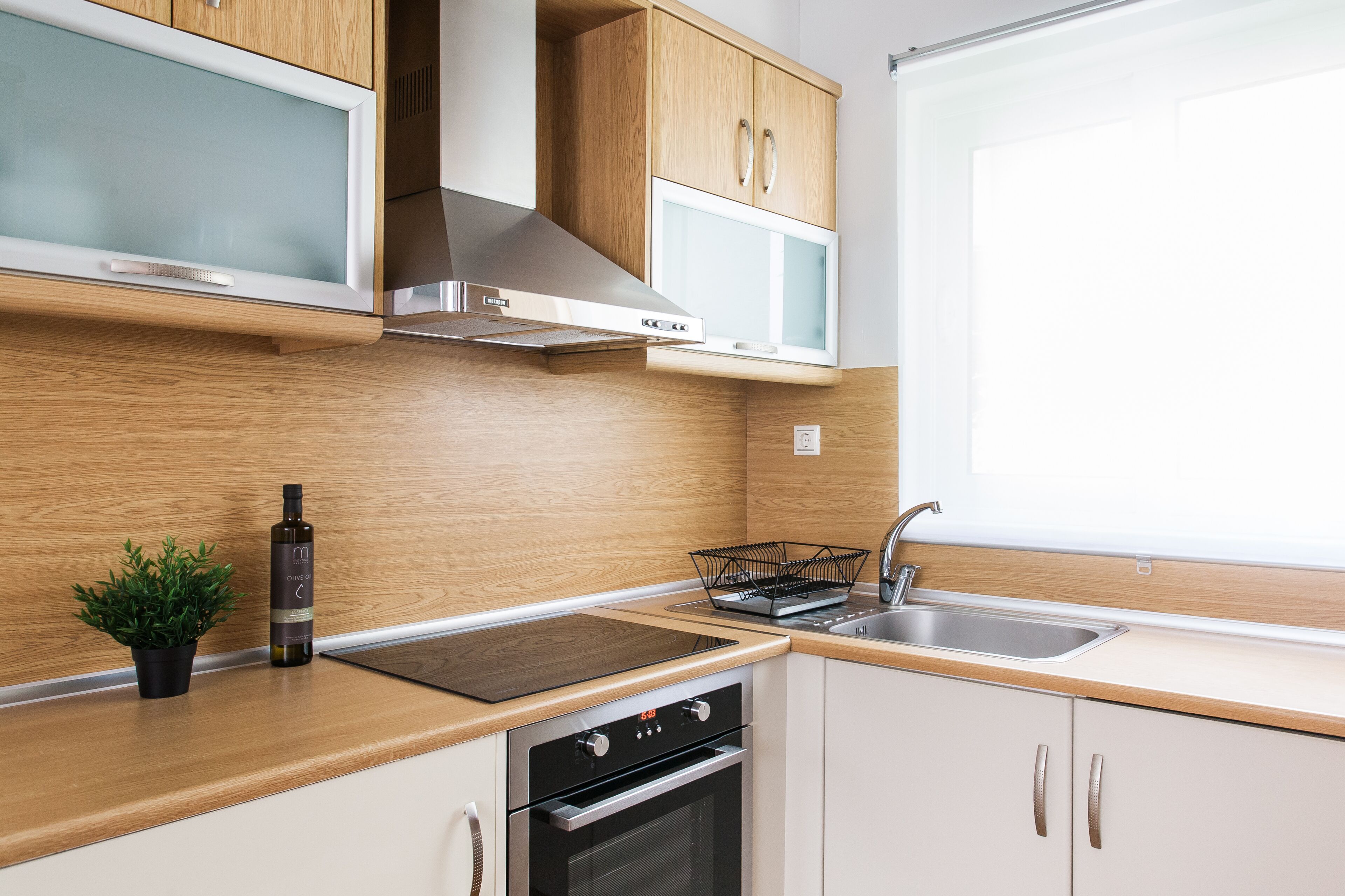 A modern kitchen with wooden cabinets, a stainless steel range hood, a built-in microwave, and a dishwasher.
