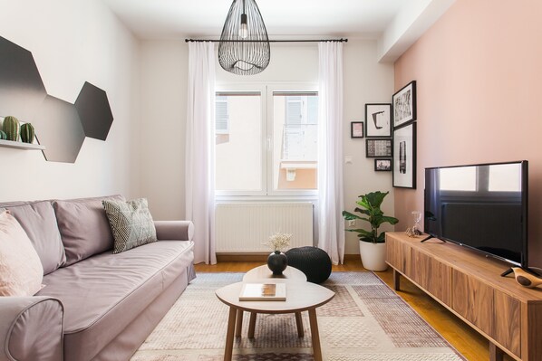 Un salon moderne avec un canapé, une table basse, un téléviseur et une plante en pot.