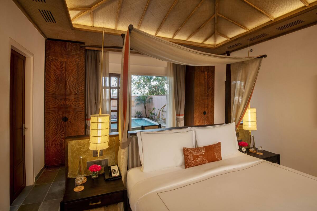A hotel room with a bed, bedside lamps, a nightstand, a telephone, and a view of a pool.
