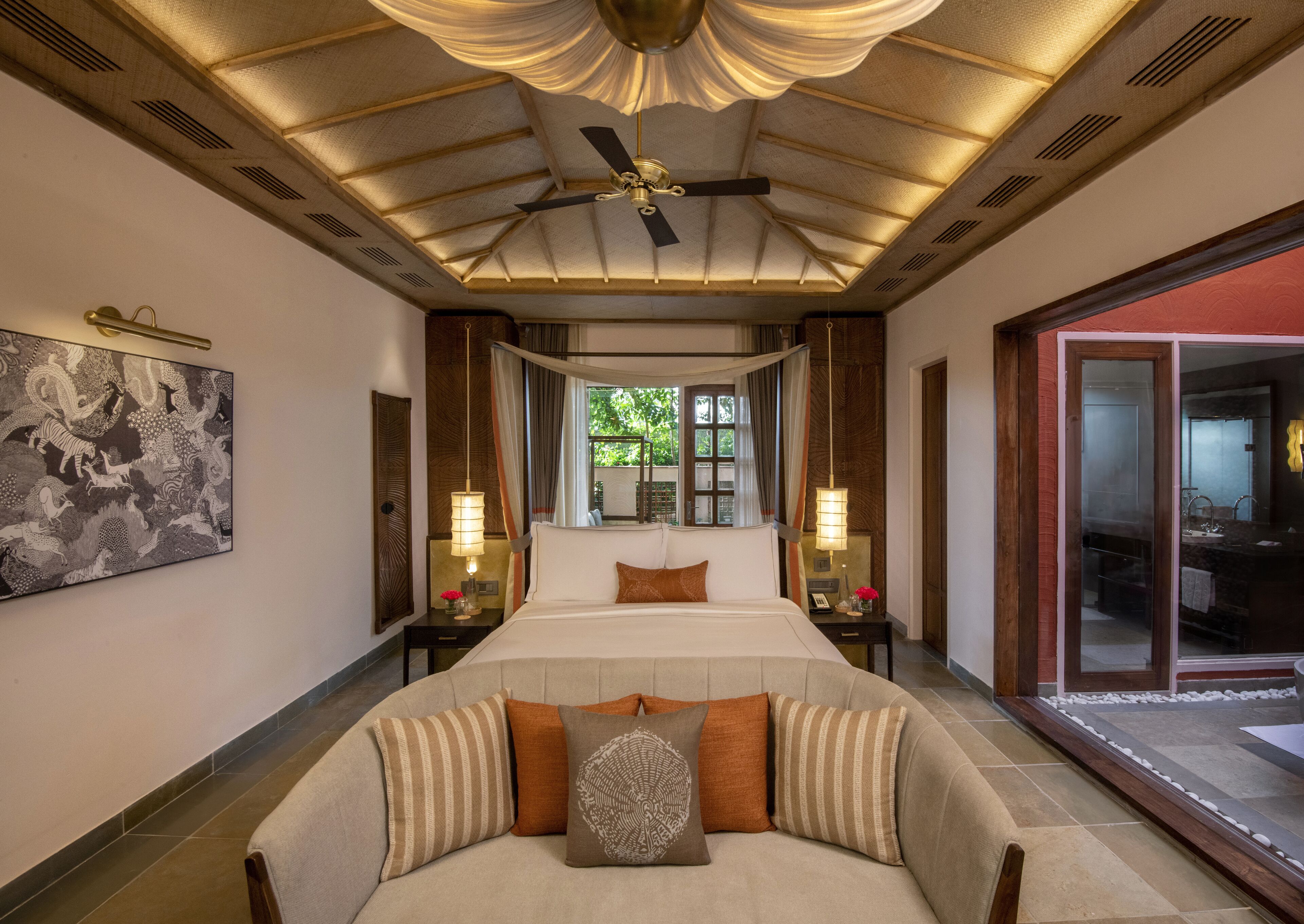 A spacious bedroom with a large bed, a ceiling fan, and a view of the outdoors through a glass door.