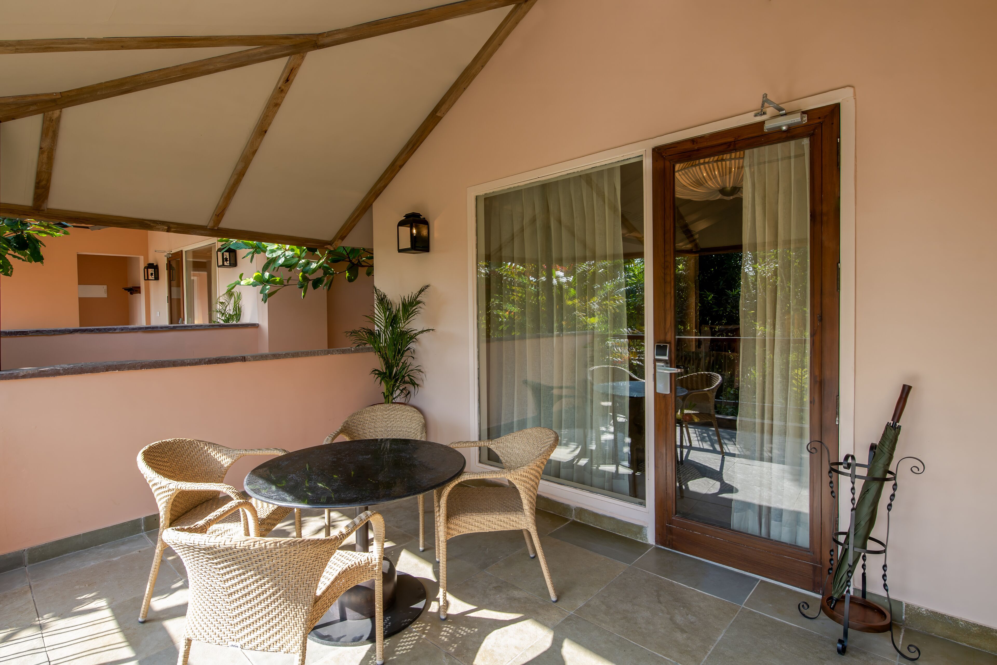 A covered patio with wicker chairs and a table, a sliding glass door, and a potted plant.
